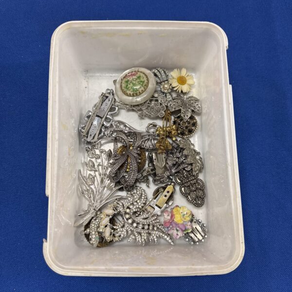 Vintage costume jewellery brooches in a tub, a colourful collection.