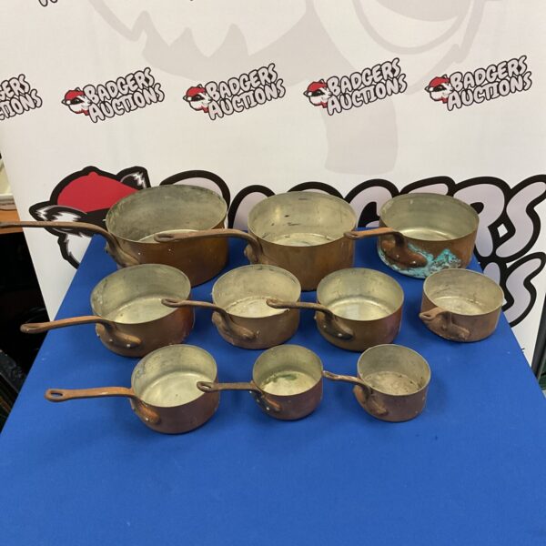 Set of ten vintage copper pans with long handles.