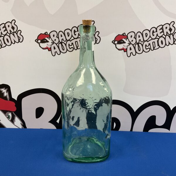 Vintage green glass bottle with embossed sun pattern.