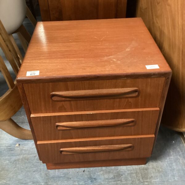 Vintage G Plan three-drawer bedside cabinet in warm wood tone.