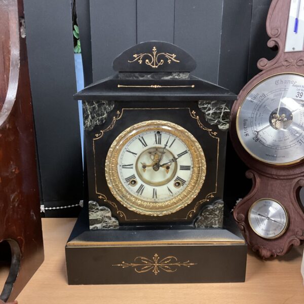 Side view of a Victorian slate mantle clock with weather indicators.
