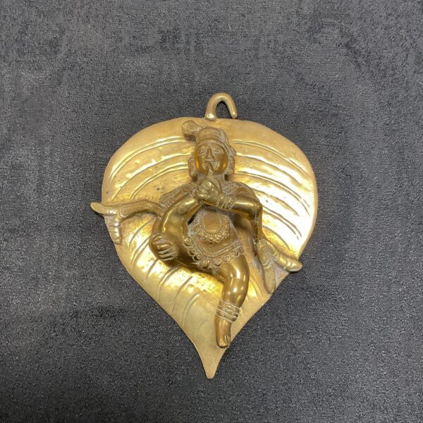 Vintage Indian brass statue of Bal Krishna seated on a leaf.