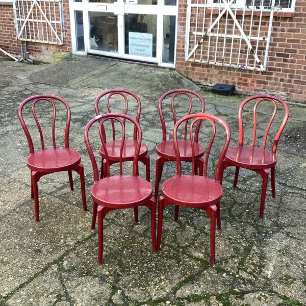 Six vintage plastic garden chairs in a garden setting.