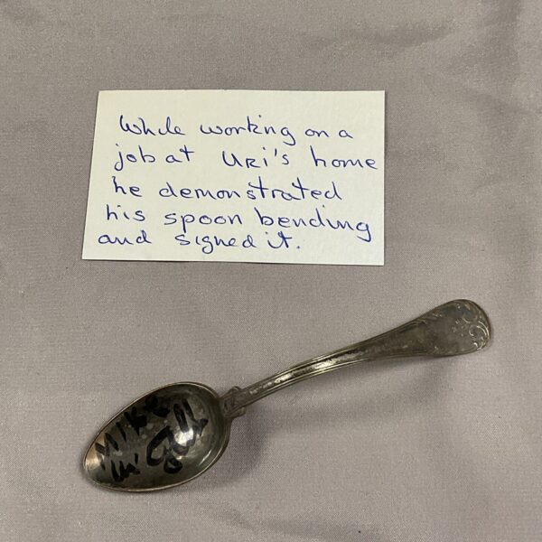 Signed Uri Geller bent spoon, a unique paranormal collectible.