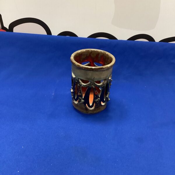 Handmade glazed ceramic tea light holder with intricate design.