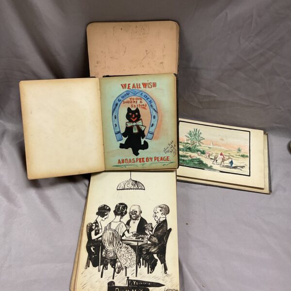 Stack of three early 1900s pocket books with watercolour illustrations.