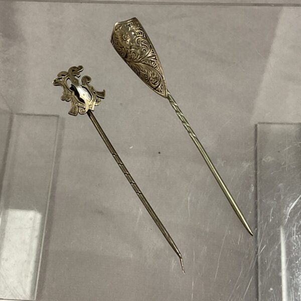 Antique white metal stick pin pair with floral designs.