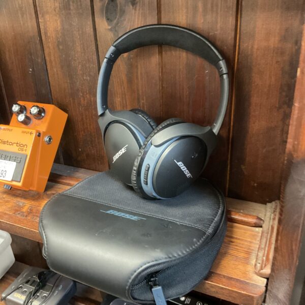 Black Bose wireless headphones on a shelf.