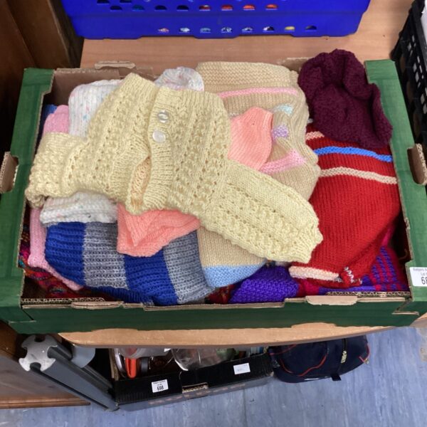 A tray of colourful knitted cardigans for babies and young children.