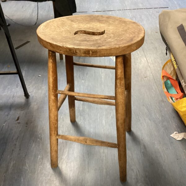Vintage wooden stool with a circular seat and three legs.