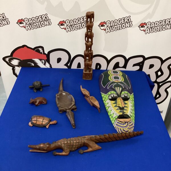 Selection of hand-carved wooden figures including African mask and animal carvings.
