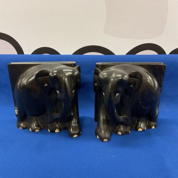 Pair of vintage ebony elephant bookends on a dark surface.