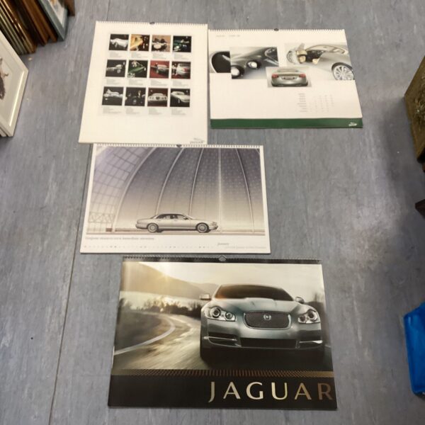 Collection of four classic Jaguar calendars for car enthusiasts.