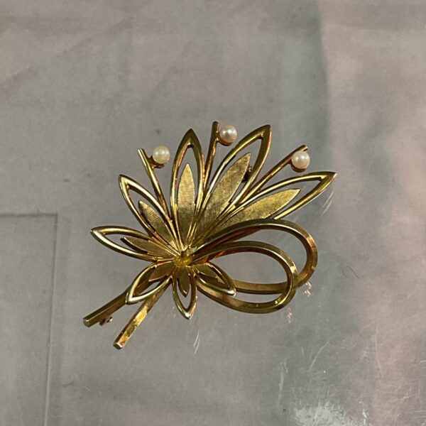 Close-up of a vintage 9ct gold seed pearl brooch.