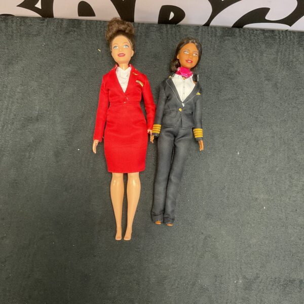 Two Virgin Airlines Barbie dolls in red and navy uniforms.