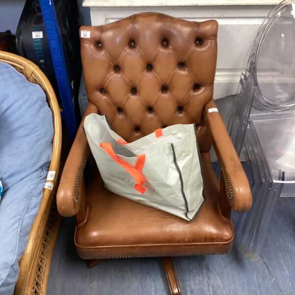 Brown leather Chesterfield captains chair with caster wheels.