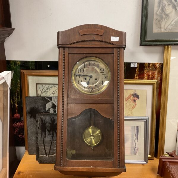 Vintage oak wall clock with Roman numerals and chiming mechanism.
