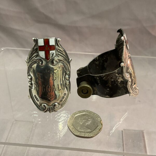 Pair of vintage E C Riggall silver bicycle badges on display.