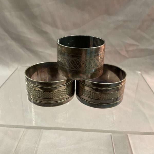 Three vintage whitemetal napkin rings with textured detail.