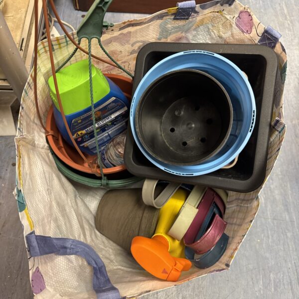 Assorted plastic plant pots and garden spray bottles in a gardening lot.