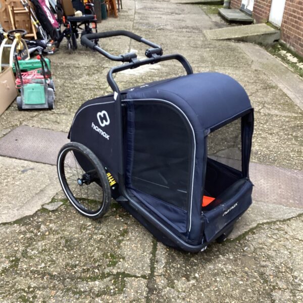 Black Hamax dog bike trailer attached to a bicycle.