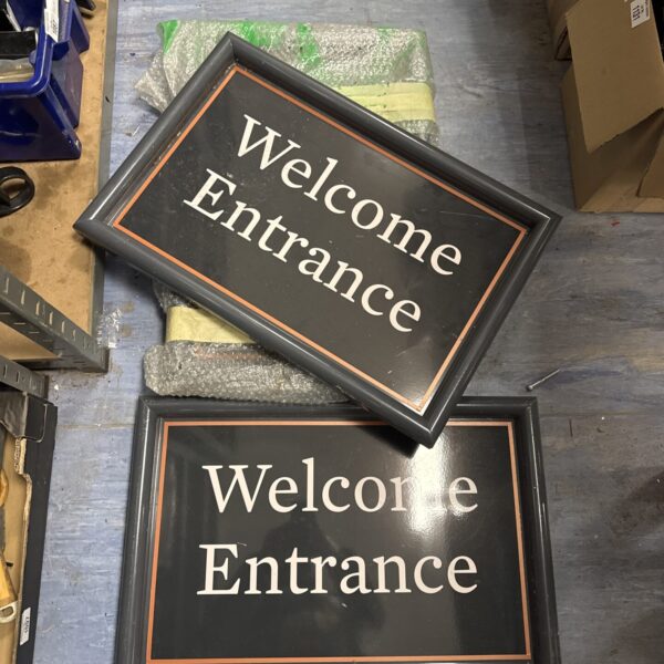 Vintage metal welcome entrance sign with peeling paint.