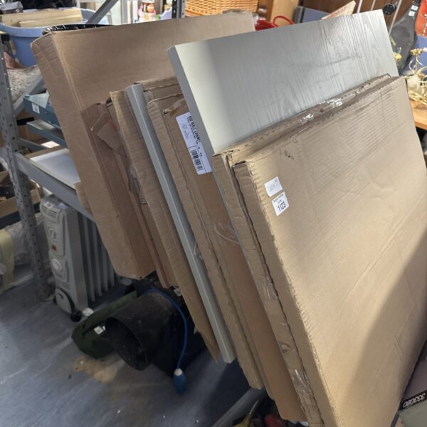Stack of light grey kitchen wall cabinets in a garage.