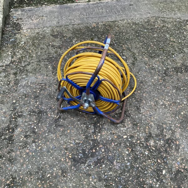 Yellow garden hose wound on a blue metal reel.