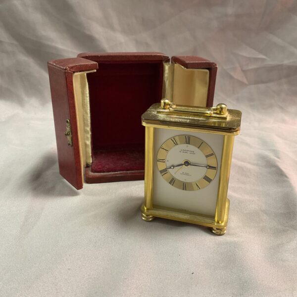 Looping brass miniature carriage clock with travel case.