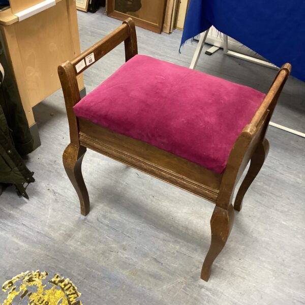 Vintage burgundy padded piano stool with wooden frame.