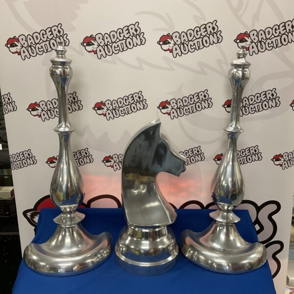Polished stainless steel chess pieces displayed on a blue surface.