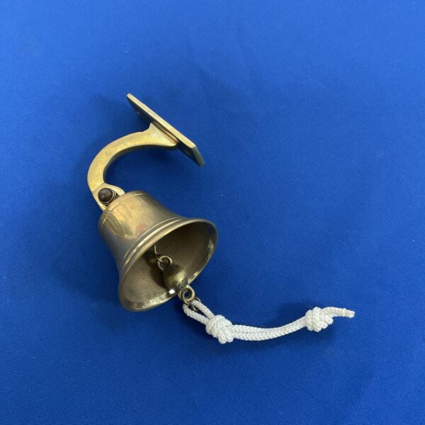 Vintage brass door bell with rope attached, classic shop hardware.