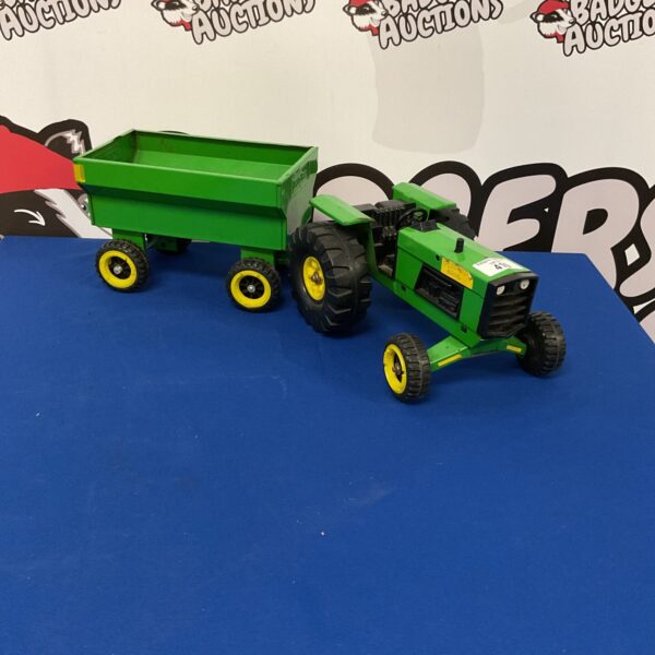 Vintage Tonka tractor with trailer on blue background.