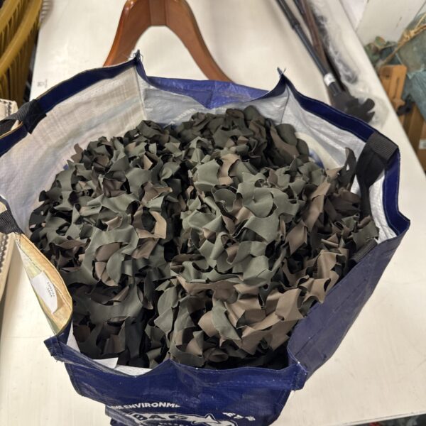 Large roll of camouflage webbing inside a blue bag.