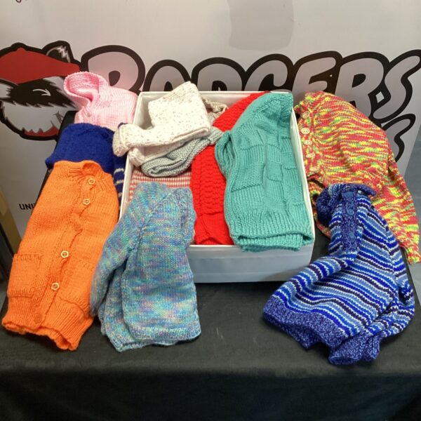 Mixed lot of colourful hand knitted cardigans and jumpers.