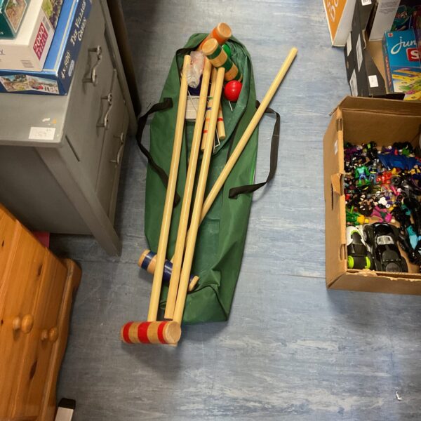 Vintage croquet set with mallets and balls in a green bag.