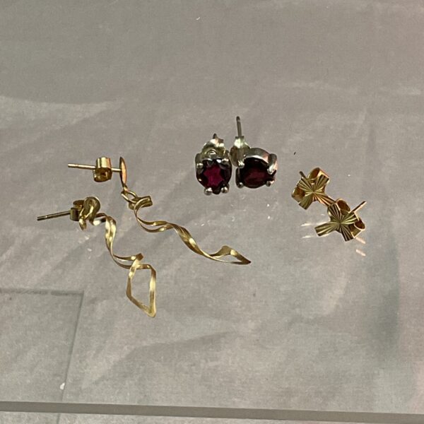 Close-up of 9ct gold and silver stud earrings on a dark background.