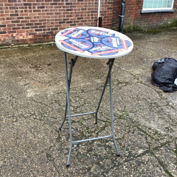 Tall round patio table in a garden setting.