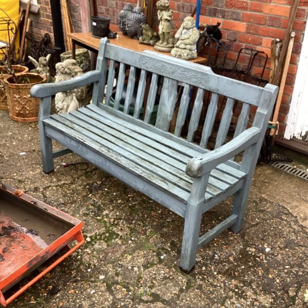 Weathered grey painted wooden garden bench in a garden setting.