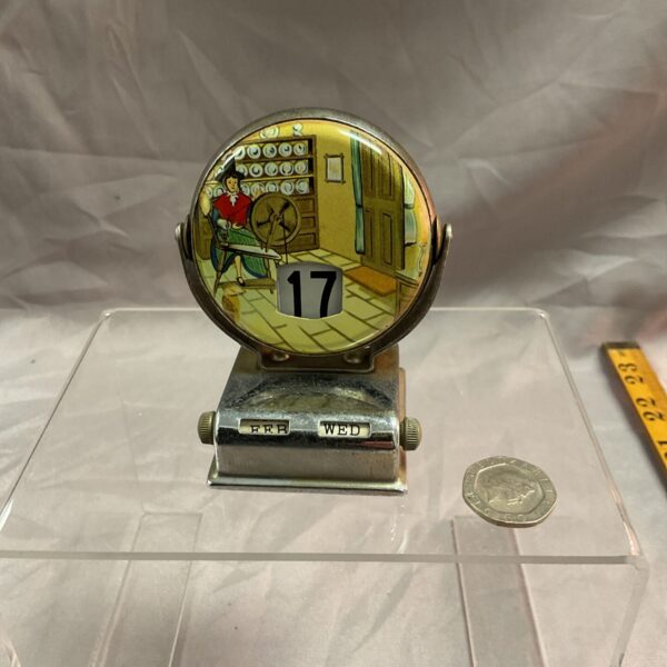 Vintage day date calendar with Welsh spinning scene on metal base.