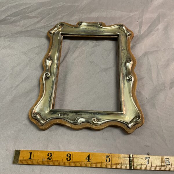 Antique silver picture frame with ornate scrolling design.