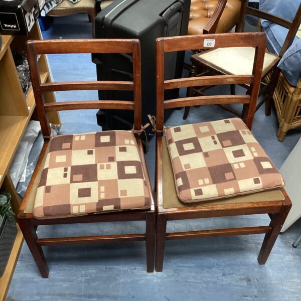 Pair of vintage dining chairs with patterned seats and stick backs.