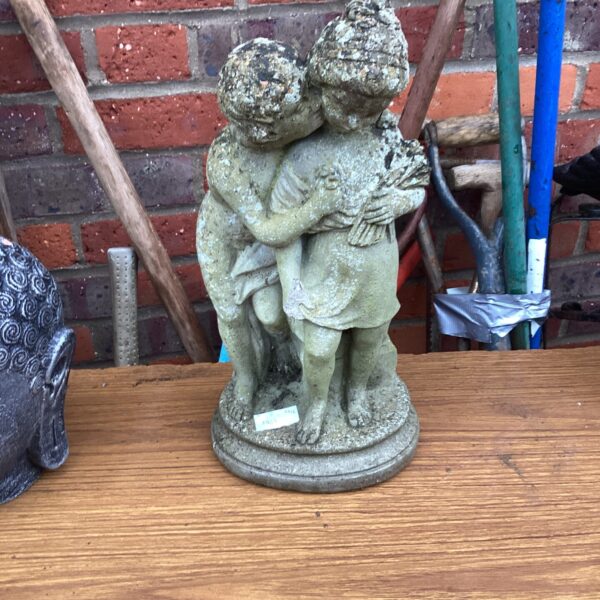 Vintage garden ornament of two hugging figures.