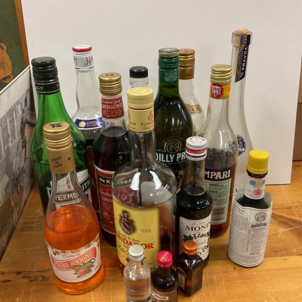 Overview of a mixed lot of part-drunk alcohol bottles.