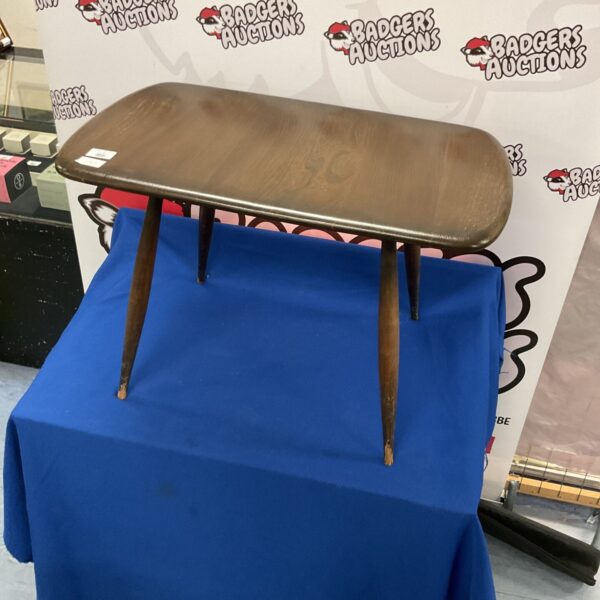 Vintage Ercol magazine table on blue backdrop.