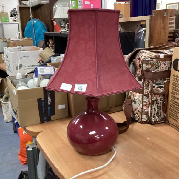 Vintage cherry red table lamp with shade on display.