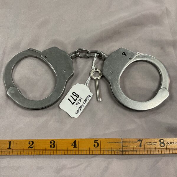 Vintage metal handcuffs with key, antique security restraints.