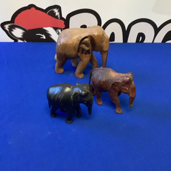 Three vintage hand-carved wooden elephant figurines on display.