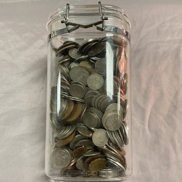 Clear jar filled with assorted vintage and modern coins.