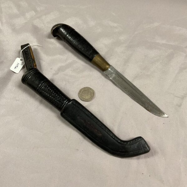 Vintage fishing knife with leather sheath and inscription on blade.